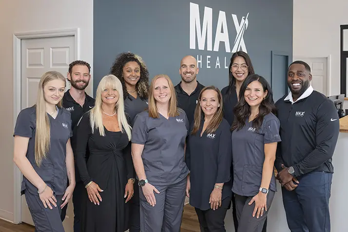 Chiropractor Huntsville AL Chrisavi Cuviello And Vinny Cuviello With Team Hero The entire team smiling in the clinic.